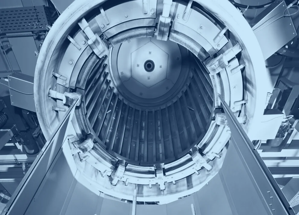 Upward view into the interior of a graphite purification furnace, showing the cylindrical chamber and vertical graphite elements