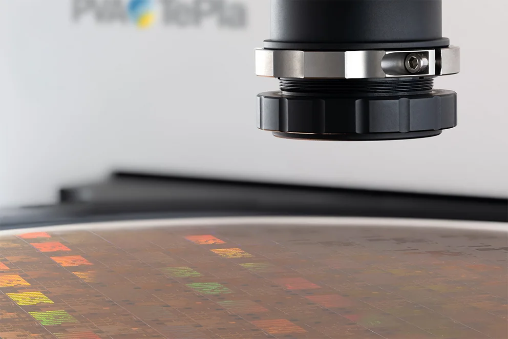 Sensor head inspecting a semiconductor wafer with colorful chip structures.