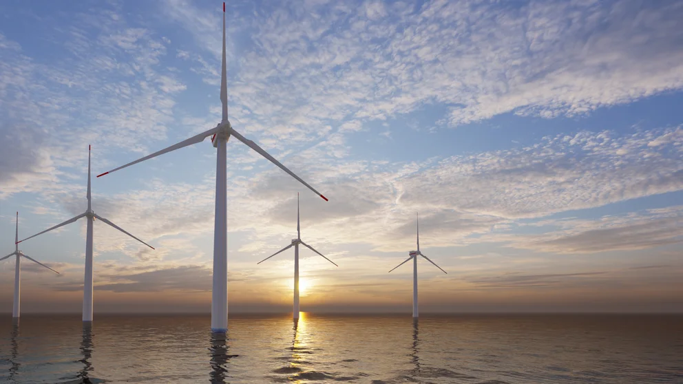 offshore wind turbines in front of a sunset