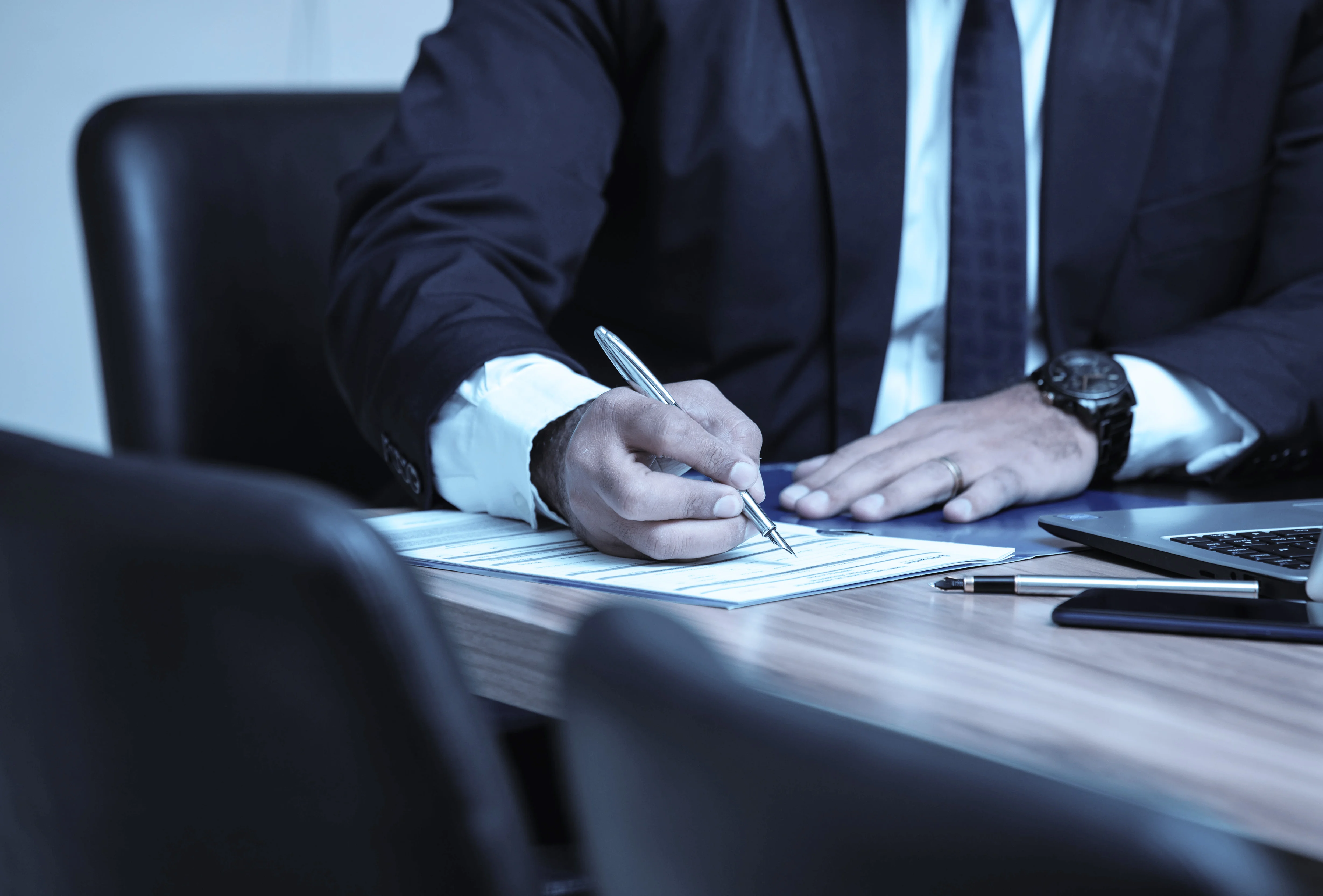 Person in a business suit signing documents at a desk