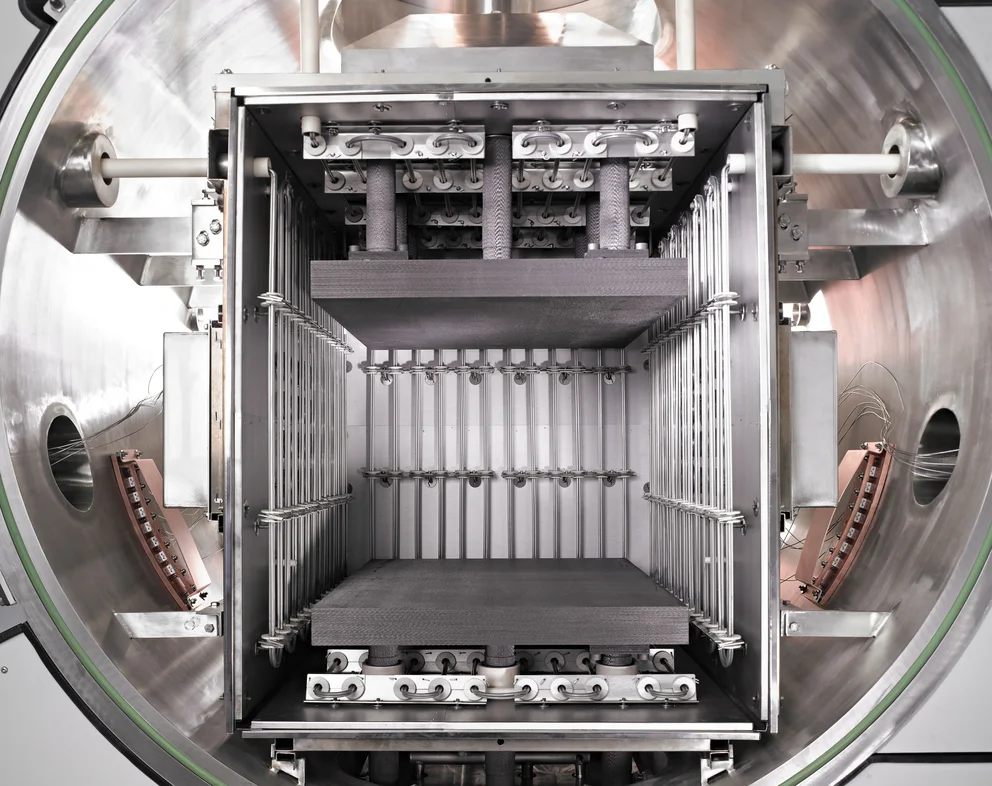 Interior view of a high vacuum furnace chamber with heating elements and substrate loading fixtures.