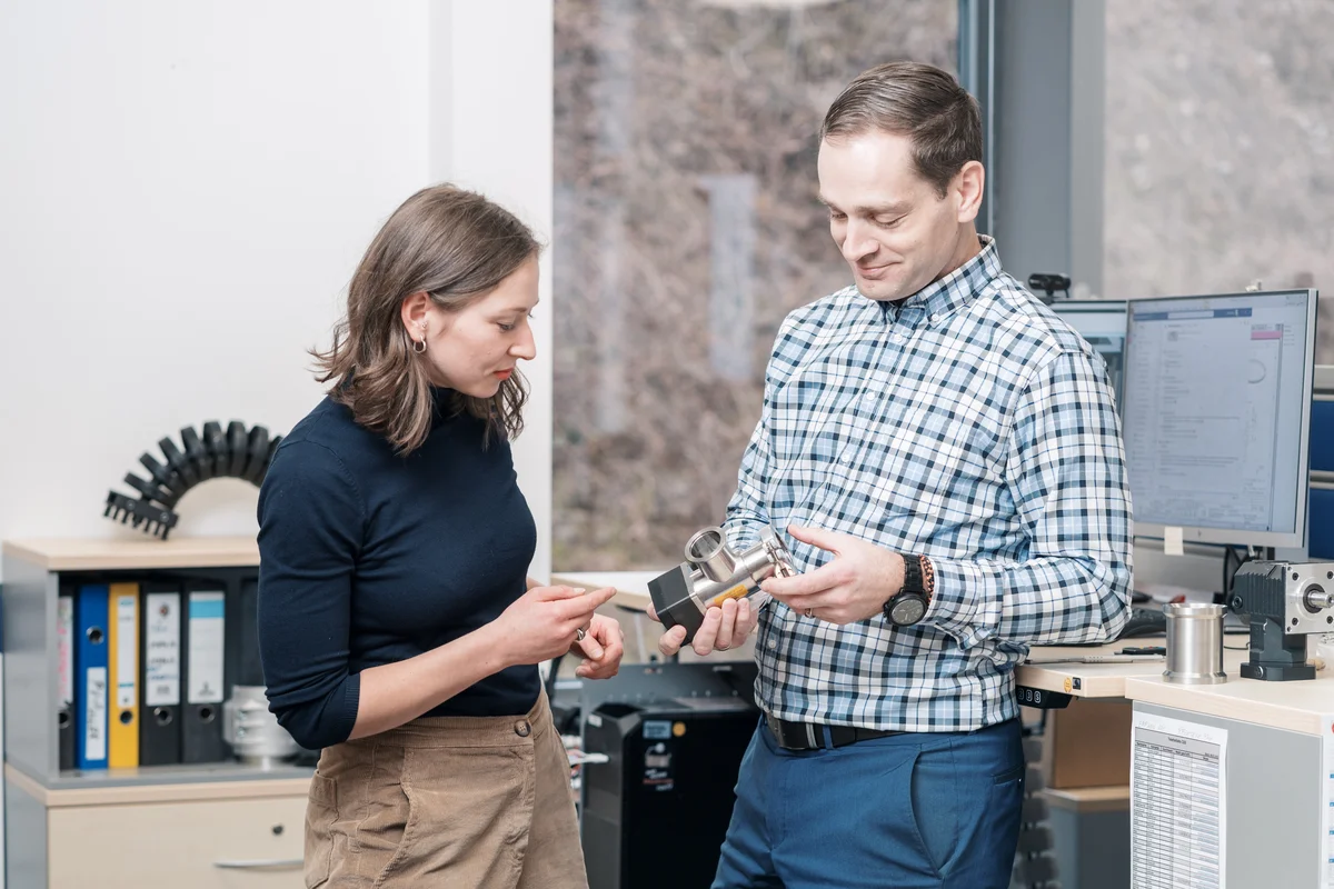 Two people discussing a technical component in an office