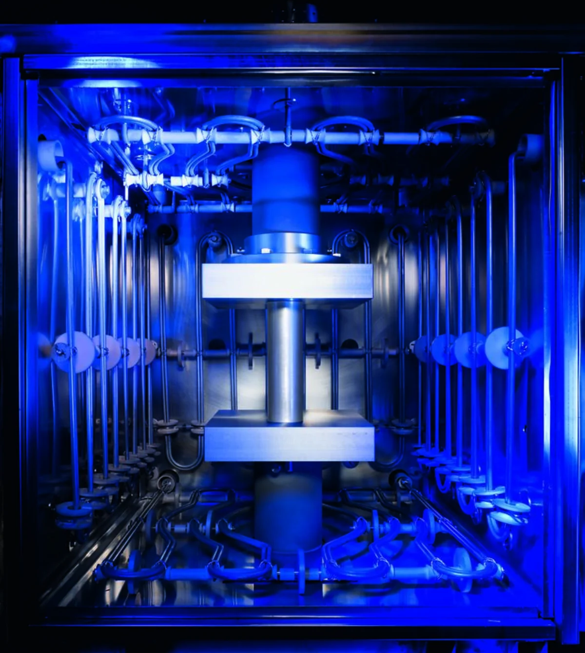 Interior of a diffusion bonding furnace chamber illuminated in blue with press platens visible.