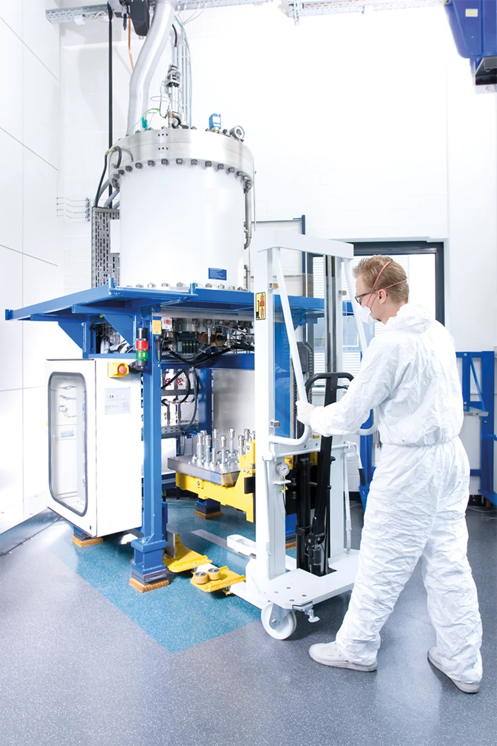 Operator in cleanroom suit working with a Vertical Gradient Freeze crystal growth system