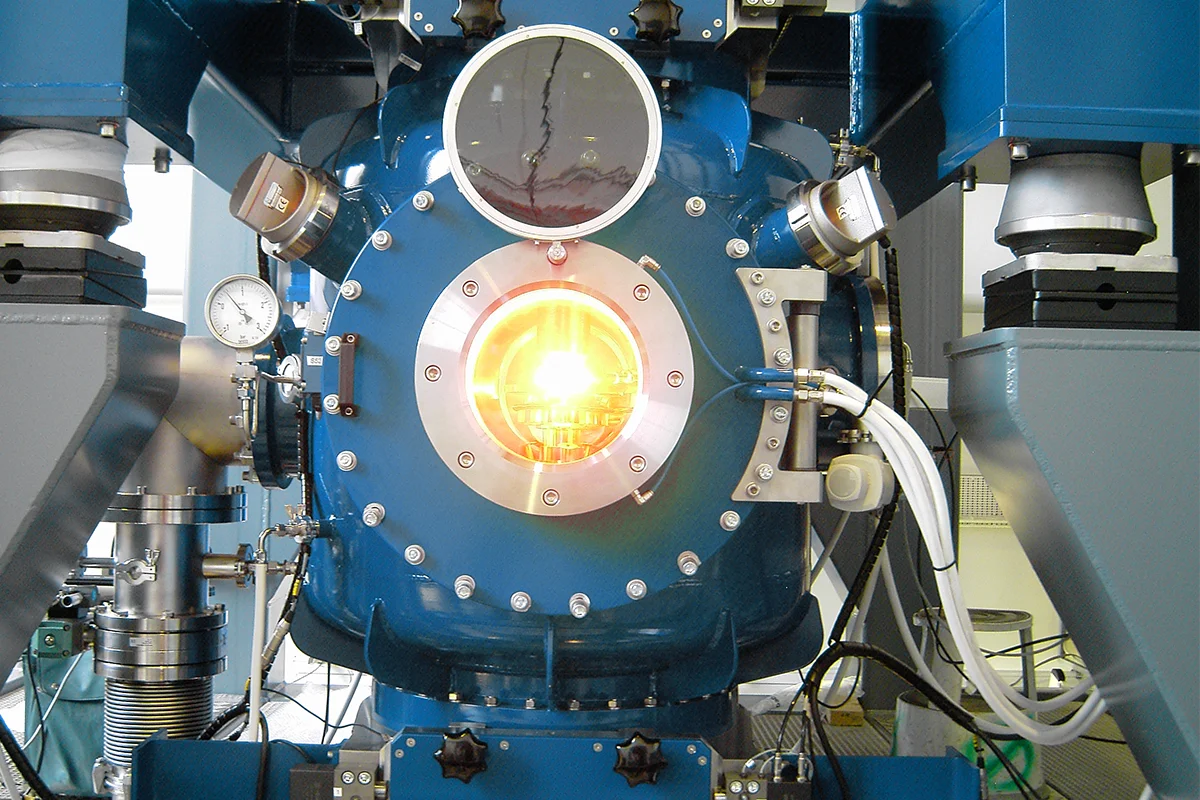 Front view of a float‑zone crystal growth chamber with visible molten silicon zone