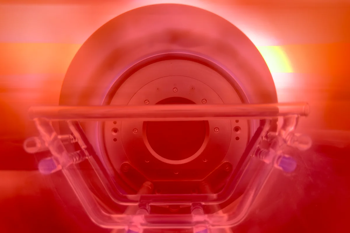 Plasma frontend interior view with glowing red-orange plasma and circular electrode.