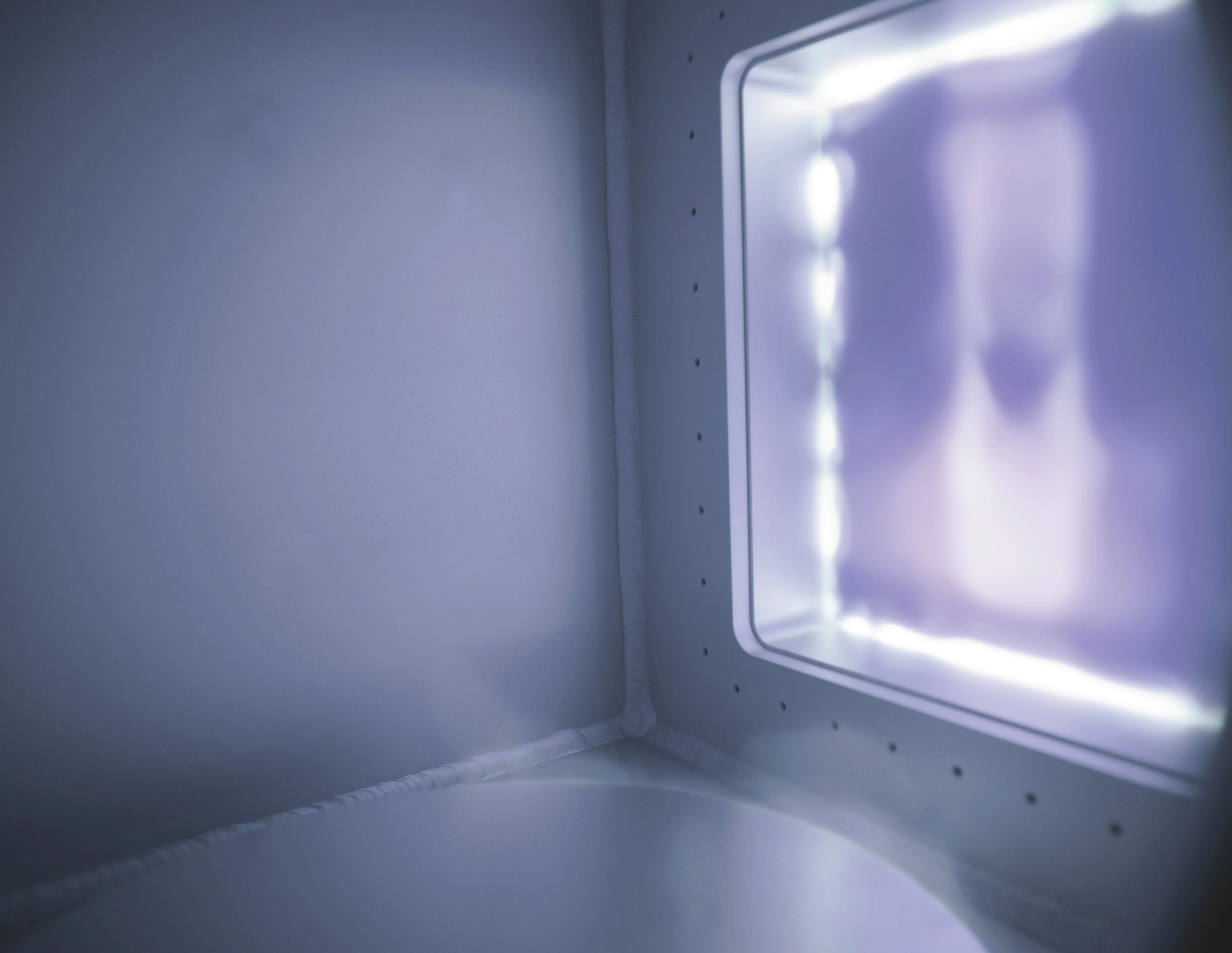 Interior view of an illuminated plasma chamber with glowing light and reflective walls.