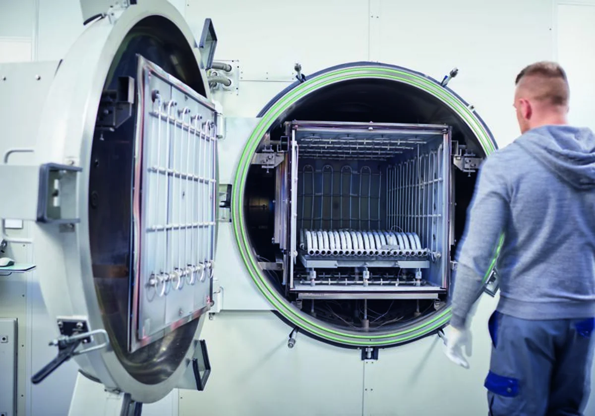 Worker loads metal components into the large open chamber of an high vacuum brazing furnace.